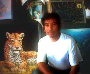 Tijuana Black Velvet Elvis artist Jorge Terrones sitting in front of a 