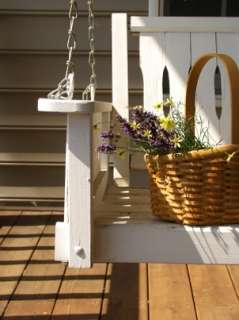 White wooden porch swing holds a basket of flowers