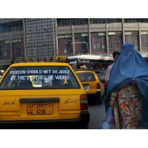  An Afghan Woman Clad in a Burqa Walks Next to a Taxi in 